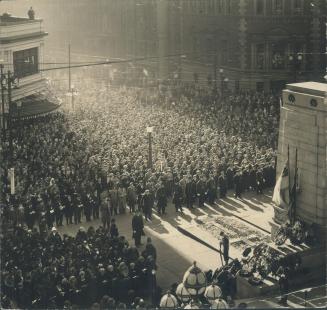 A solemn crowd of people gathered next to the Toronto cenotaph at a wreath-laying for Remembran…