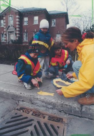 Earth Week message. Parent Mary Jarvis helps Jacob Jarvis, 8, Willy Felsky, 8, and Ali Jarvis, 5, paint an acrylic fish near a storm drain outside Whi(...)