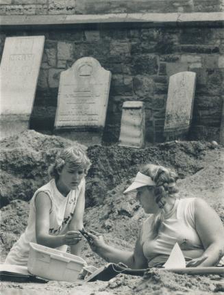 Old graveyard yields secrets. Archeology students Barbara Redfearn, left, and Lorelyn Giese share a find in the graveyard of St. Thomas Church in Bell(...)