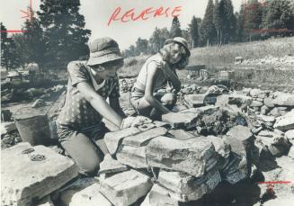 Two women, surrounded by rocks, working in the sun.
