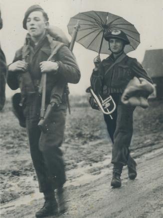 This Canadian soldier uses a sunshade to keep off the weather as he marches through a Dutch village near the Canadian front. Rains have been almost co(...)