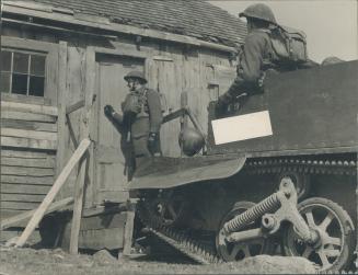 On patrol duty along the Newfoundland coast with a Bren gun carrier, Canadian troops call at a fisherman's home