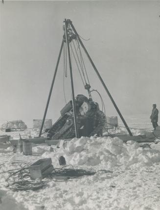 Suspended by pulleys the snowmobile is being recovered from the huge crack as the Muskox travellers beat their way south through deep mud and soft snow