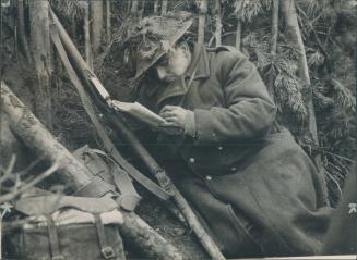 A London soldier of a literary turn of mind does a little reading in a captured German slit trench as he waits word to advance further into collapsing Germany