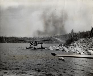 One of Seaplanes scouting fire areas for new outbreaks and rushing men to fight them is seen anchored on small lake awaiting new load of firefighters.(...)