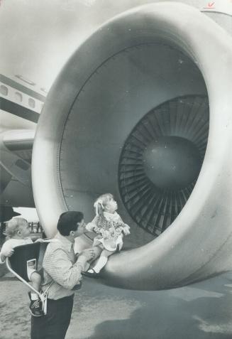 A child and the works of man. Elizabeth Walker shows the wonder of a 2-year-old as she peers into the darkness of a giant engine intake of visiting Mc(...)
