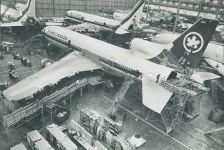 A Lockheed Tristar wearing Air Canada's colors is surrounded by scaffolding as workmen complete some of the final stages in a huge assembly hangar at (...)