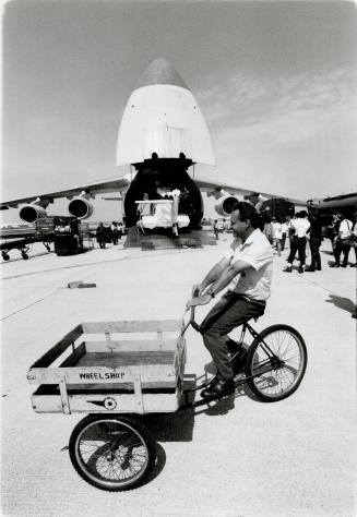 Low-tech delivery. Air Canada mechanic Tony Mallalieu pedals by on his old reliable, a parts delivery bicycle, while behind him at Pearson Internation(...)