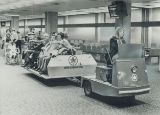 Passenger surreys, towed by electric tractors, patrol the hallway of Terminal 2 at Toronto International Airport