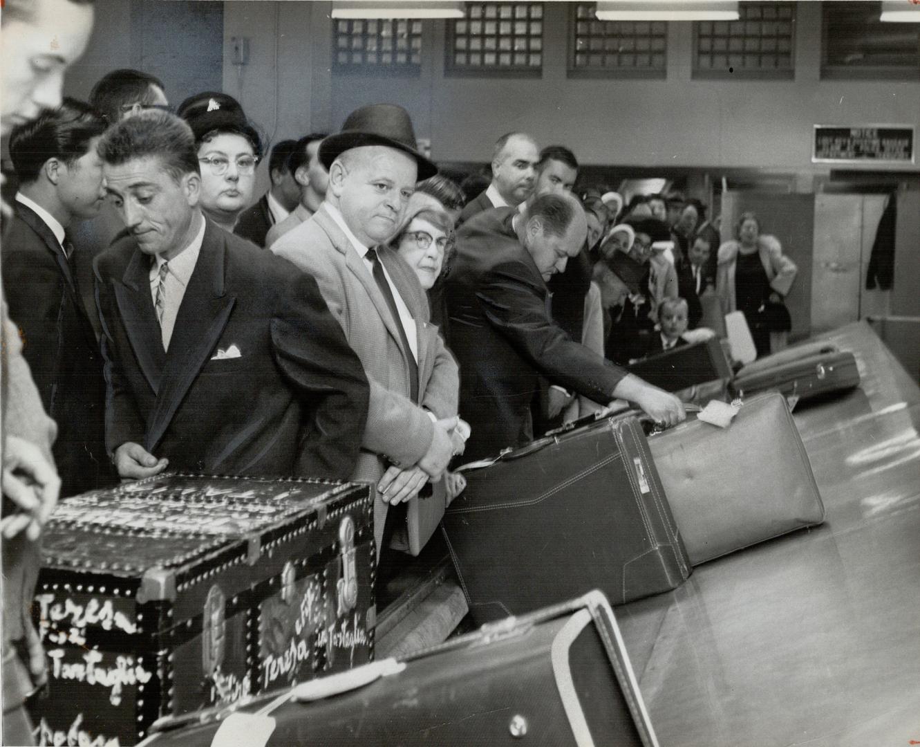 Arrivals crowd to counter seeking their luggage