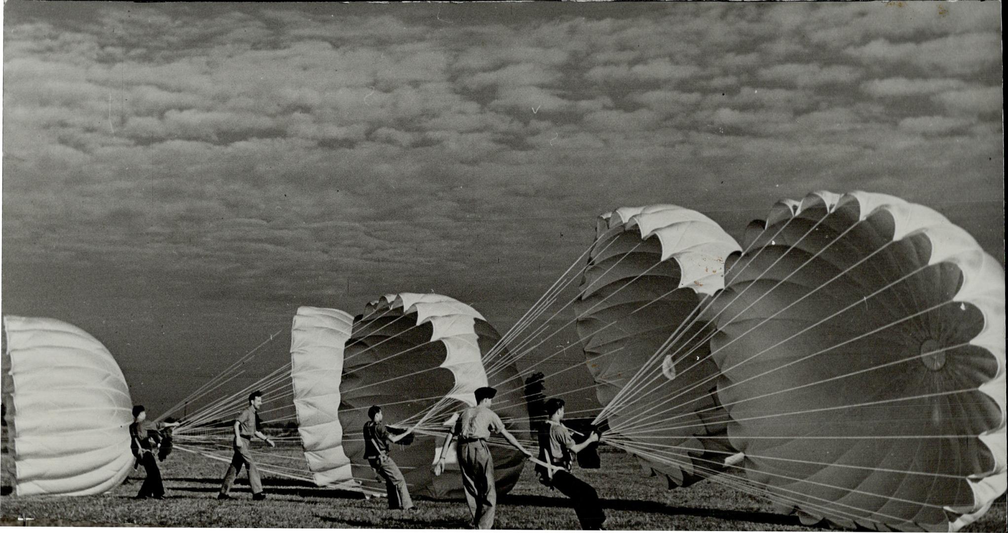 Somewhere in Ontario, at an R.C.A.F. training field, these men are learning the art of waging warfare from the skies. Handling parachutes is included (...)