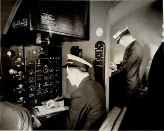 In the left foreground, the engineering officer is noting on his log readings from the dials in front of him