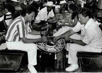 Delay on the cards: Two Canadian vacationers use a sombrero as a card table as they wait to be airlifted home from Cancun recently, following the odyssey-Thomson failures