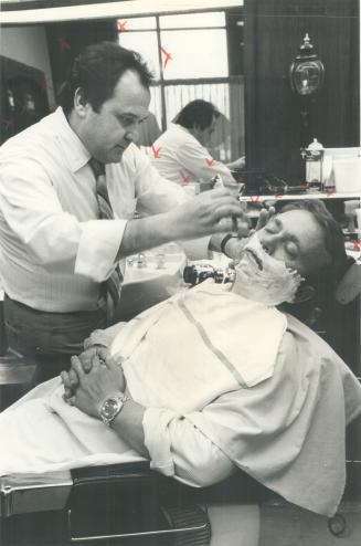 Worlds apart: The bewhiskered gent agove, The Star's Reg Innell, isn't much comfort to barbers like Thomas Brescia (right), giving Innell's photographer colleague Fred Ross a close, cool one