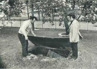 A mass grave for infants, kept open and covered with a sheet of plywood, is examined yesterday by North York Controller Mel Lastman (right) and David (...)