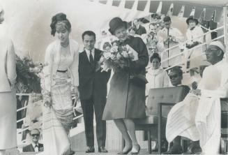 Presentation of flowers is made to Mrs. Robert Shaw, official Expo hostess, by Yiyi-chit Maung, 24, of Rangoon at yesterday's visit to the fair by Bri(...)