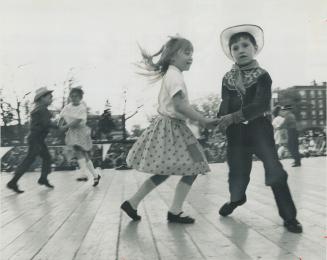 Reeling off 100 years. Youngsters from St. William's Separate School do square dance in centennial show in Kew Gardens presented last night by 10 East(...)