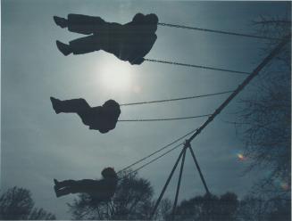 Pix of some children, silhouettes, on swing set, with burning sun