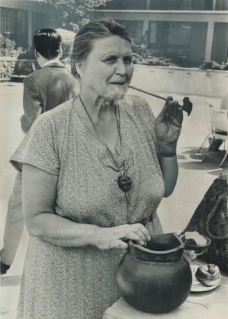 Mrs. Alla Bjorkman with pipe. Exhibiting at outdoor Art Show