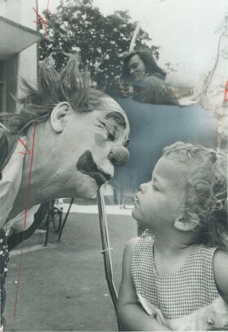 Puckeirng up, Fifi, official clown of the Canadian National Exhibition, gets ready to kiss 2-year-old Lisa Bavington of Mississauga, one of thousands (...)