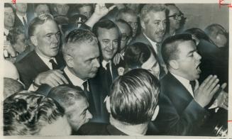 Grimly fighting diefenbaker is surrounded by admirers in crowded lobby as he arrives at hotel today, Joel Aldred, Toronto announcer, has his hands on (...)