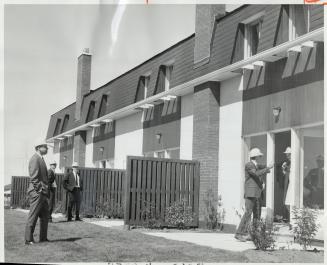 Government, construction and financial representatives watch as workmen use new concrete technique in experimental Scarborough town house project