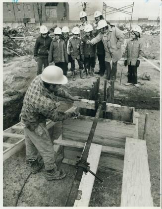 Faces intent, a group of boys from Elkhorn Public School, watch a construction workman adjust formwork on the building site of a large apartment proje(...)