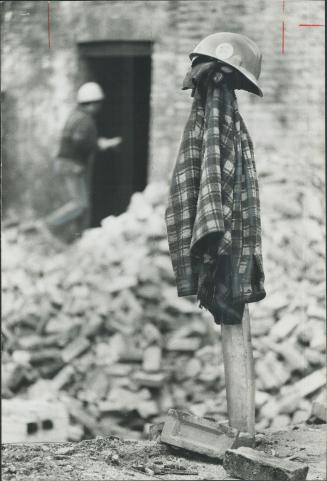 Plaid jacket and hardhat of a wrecker hang against background of heaped-up bricks as a huge segment of Toronto vanishes to make way for gleaming modernity