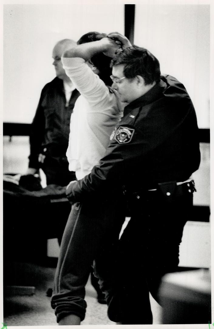 An inspector (left) pats down a Detroit-bound Canadian