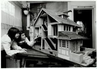 Caroline Evans, 10, left, looks into dollhouse with friend Rosalie Donaldson, 11, whose father Gordon built it