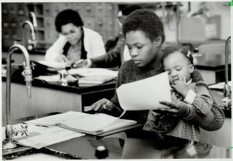 Student mom: Carol Campbell tries to study while holding her daughter, Karen, 2, who seems a little bored by it all