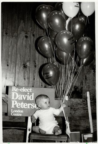 A baby held balloons in Peterson's home riding