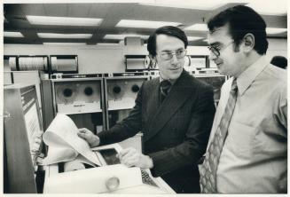 Dick Paterson (glasses) exec director of computer services division talks with Manager of Computer Centre Richard Flis as they examine print out material