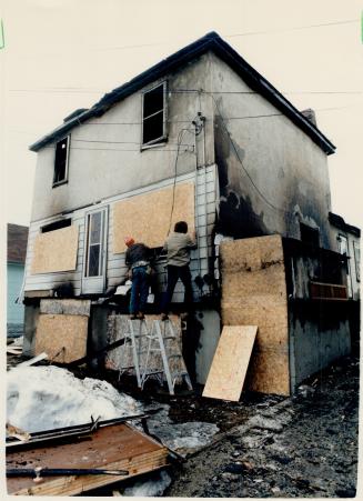 Spill aftermath: Workers board up a home destroyed yesterday by fire after gasoline leaked into the Timmins sewer system