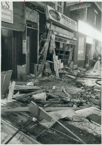 Smashed by explosions, debris litters the street in front of a wrecked delicatessen on Danforth Ave