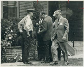 Examining damage from bomb, J. H. Ready, vice-president of Hawker Siddeley, handkerchief in breast-pocket, walks in front of his Etobicoke home with police