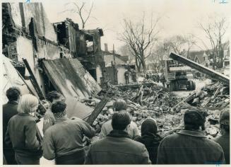 Debris of explosion on St. Clair Ave. is proved by police yesterday as spectators in foreground watch. Last night the searchers found the body of a yo(...)