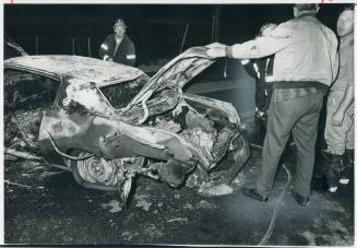 Shattered wreckage of a car rented by Arthur Roman, of Thornhill, is examined by detective Sgt