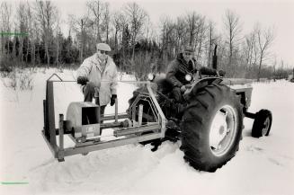 New on the farm: Sam Petetski stands behind a tractor with his foot on The Beaver, his pet stump grinder