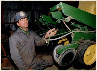 Stratford farmer Dennis Dow checks nozzle on sprayer linked to his tractor