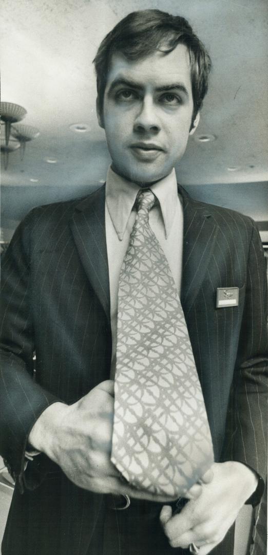 Salesman Bernie Morin of The Peacock men's shop shows off one of new wide ties, part of a booming new $20 million-a-year business. Output, sales are soaring