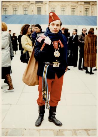 Soviet Chic, with navy wool tunic, woven sash at the waist and spare sash rolled up at the shoulder, heavy medals around the neck and an unorthodox version of the fez