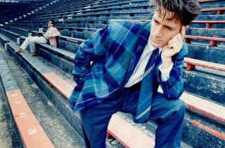 Above foreground, lightweight checked linen sports jacket in shades of blue, $350, is worn with a bright green and white striped shirt, $120, blue tro(...)