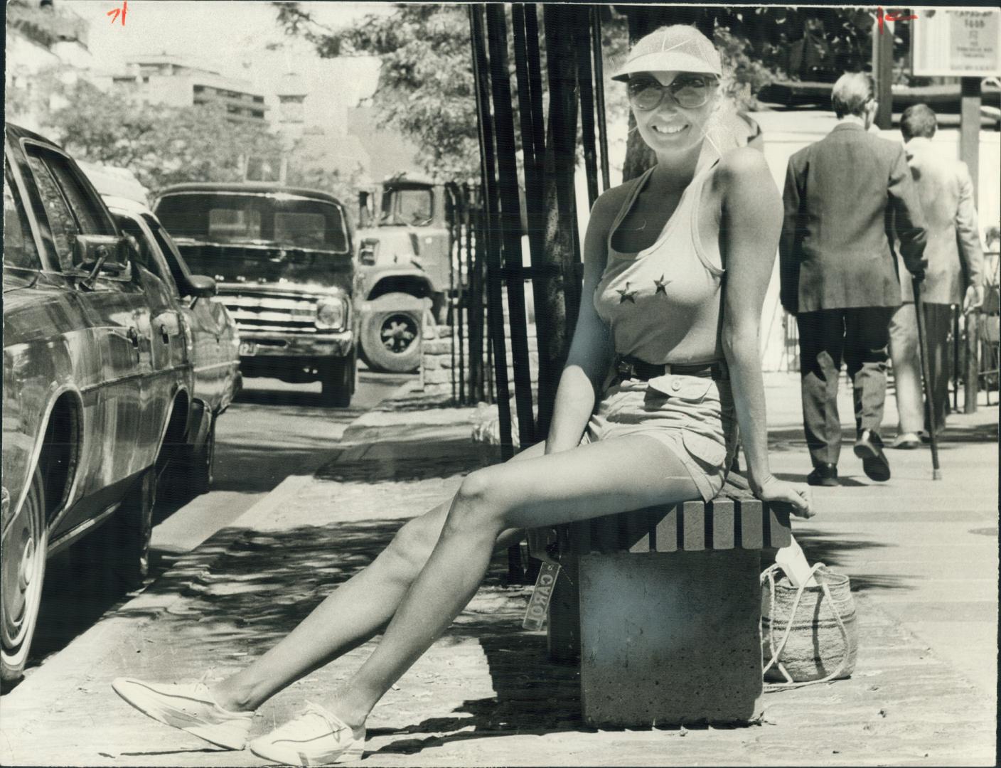 Carol Lawrence, model, relaxes in the warm sun on her day off wearing khaki shorts and a matching cotton knit T-shirt with red stars on the front. I l(...)