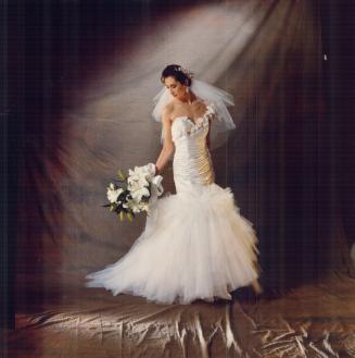 The Couture Bride wears a ruched silk gown with French beaded lace insets and layered tulle skirt, $3,600, Guzzo