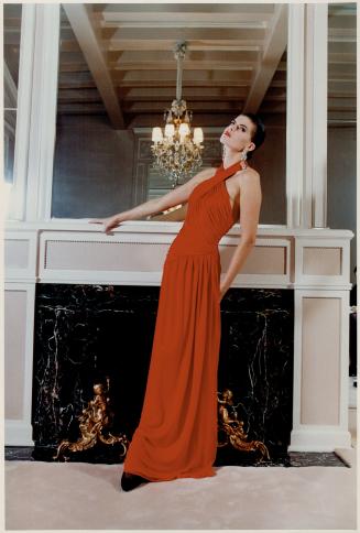 U.S.A., John Anthony's dramatic floor-length red silk matte jersey evening gown with halter neckline, draped torso and dropped waistline
