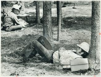 A firefighter relaxes against a tree at Ignace base camp before going in for a shift at the fire front
