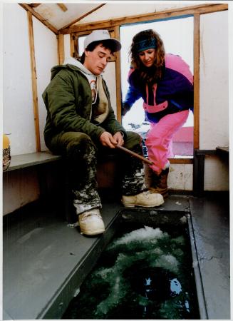 Hard-water habit: Jamie Eillis dips a line in a Lake Simcoe ice hut while Karyn James looks on