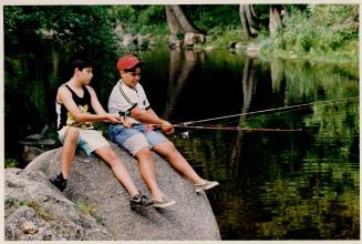 Waiting game: Patrick Araya, 10, left, and his cousin David Araya, 12, try their luck in Credit River