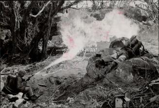 These two U.S. marine privates, with portable flame-throwing equipment, throw a searing wall of fire into a Japanese-held pillbox which blocked the way to lwo Jima's Mount Suribachi. [incomplete]